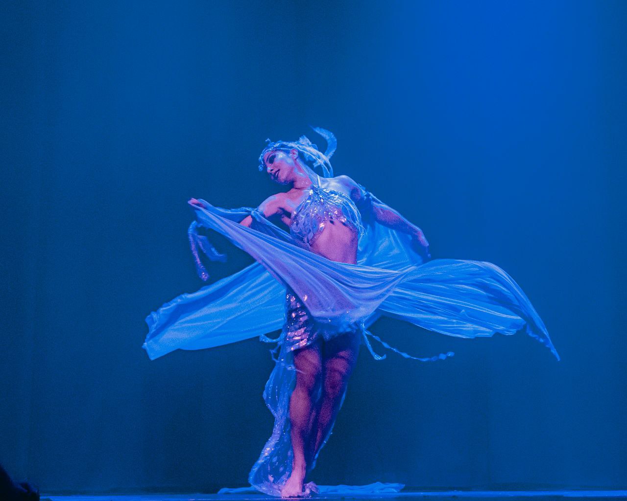 Elizabeth Khard dancing with a flowing veil in blue stage light
