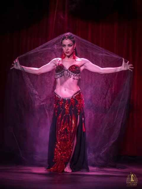Elizabeth Khard performing with a veil on stage in red light