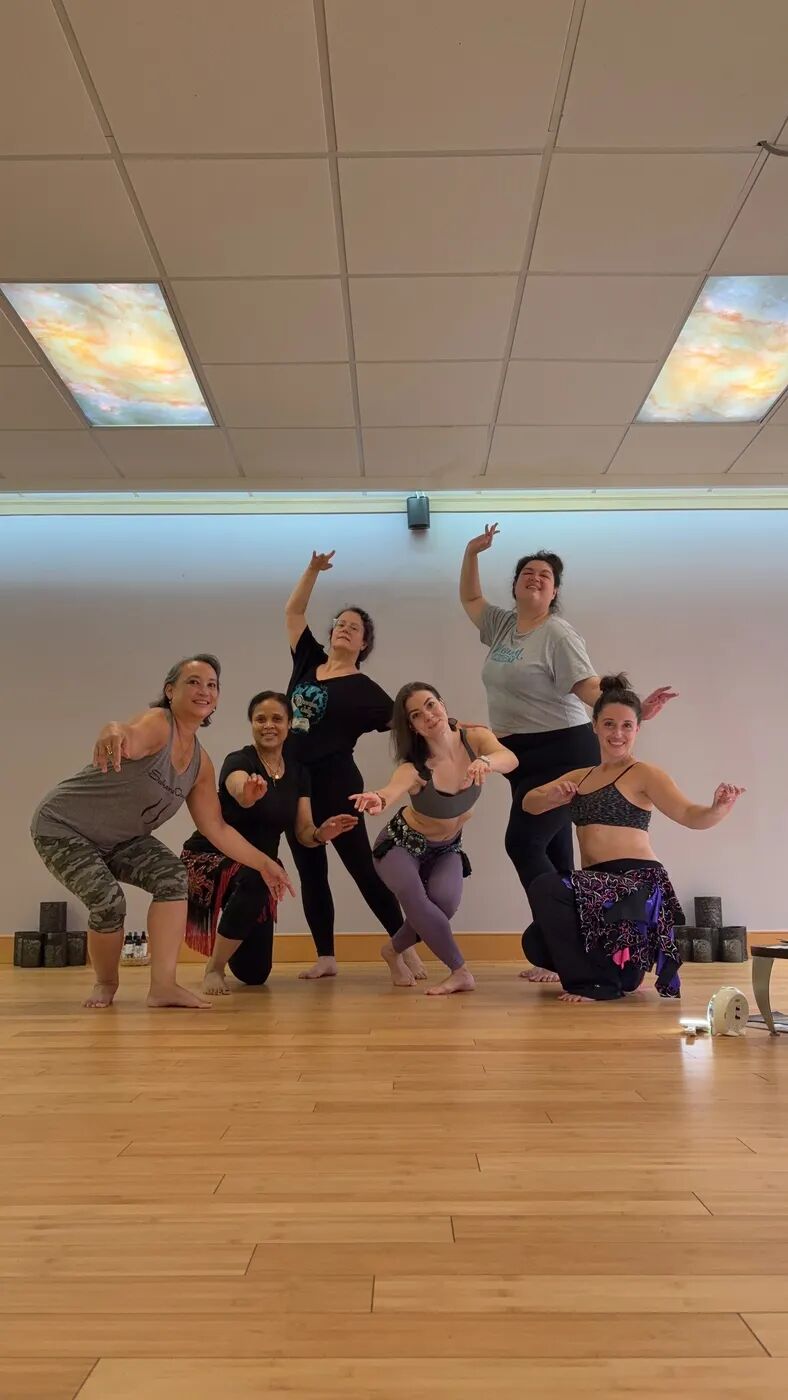 Dancers striking a playful pose together in the studio while rehearsing for the August Hafla