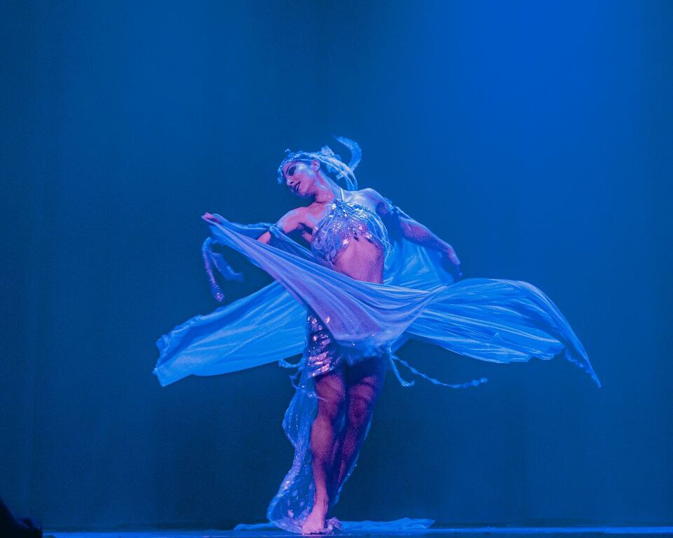 Elizabeth Khard dancing with a flowing veil in blue stage light