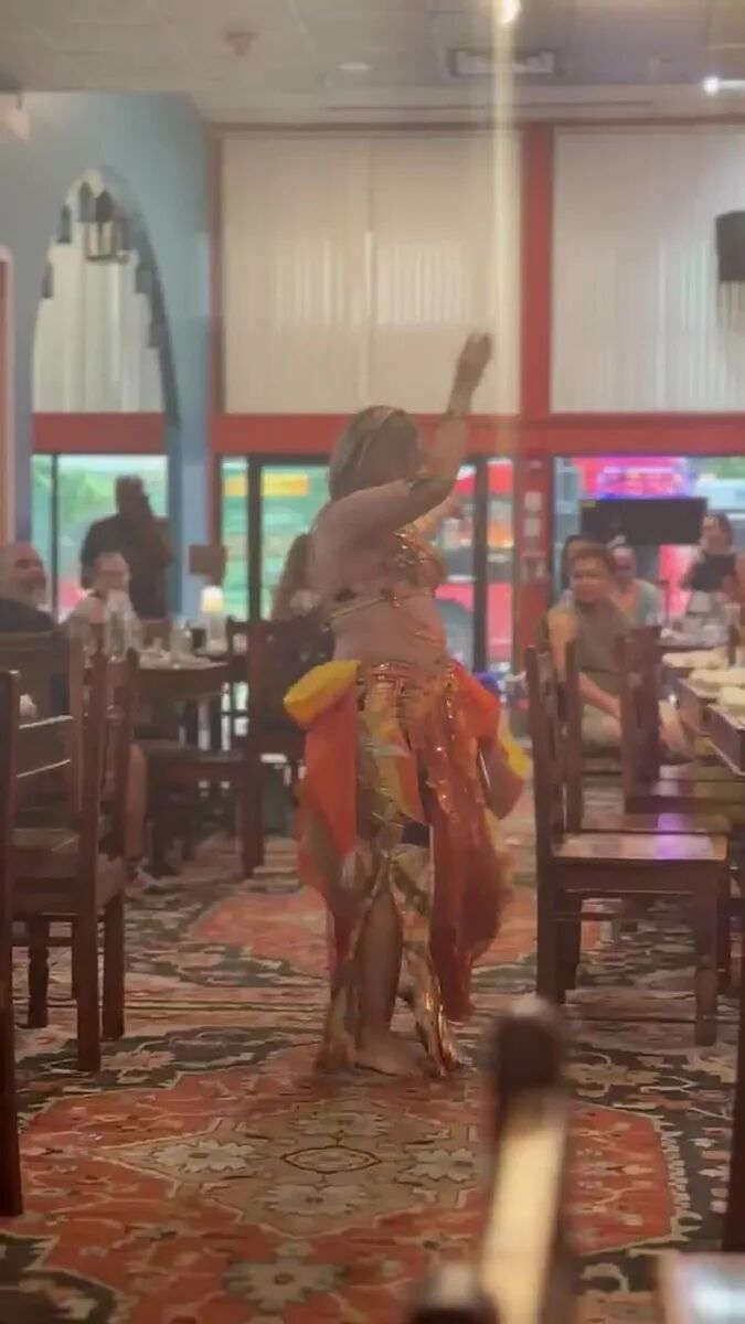 Dancer in red and orange performing on the floor at the July Hafla