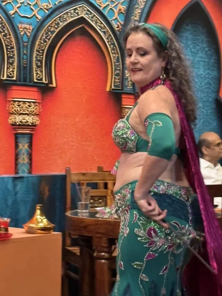 Dancer in teal and purple performing by the arch at the inaugural Hafla
