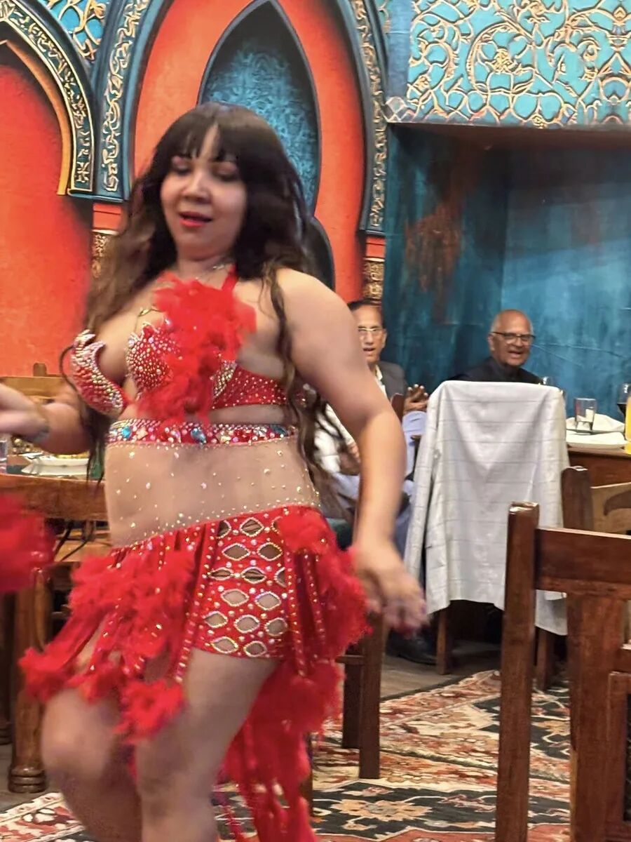 Dancer in a red feathered costume performing at the inaugural Hafla