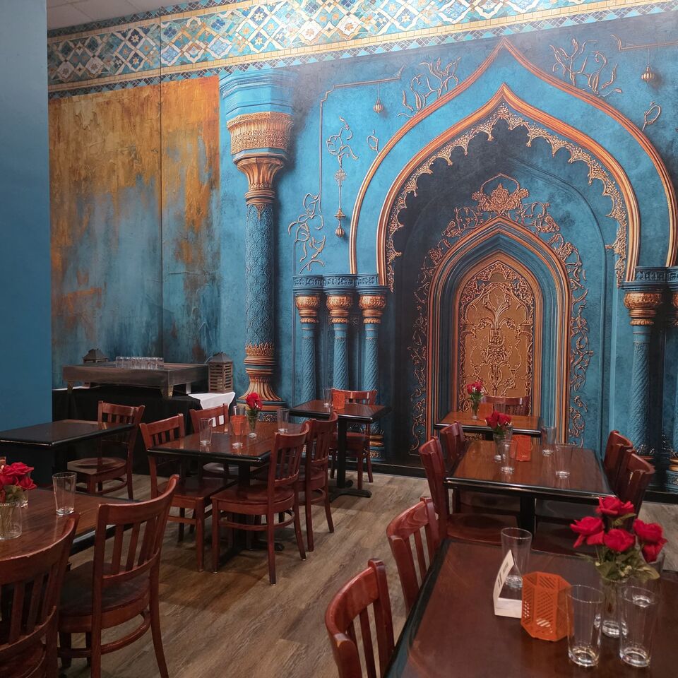 The front dining room at Marrakesh DC with carved blue and gold Moorish archways and set tables