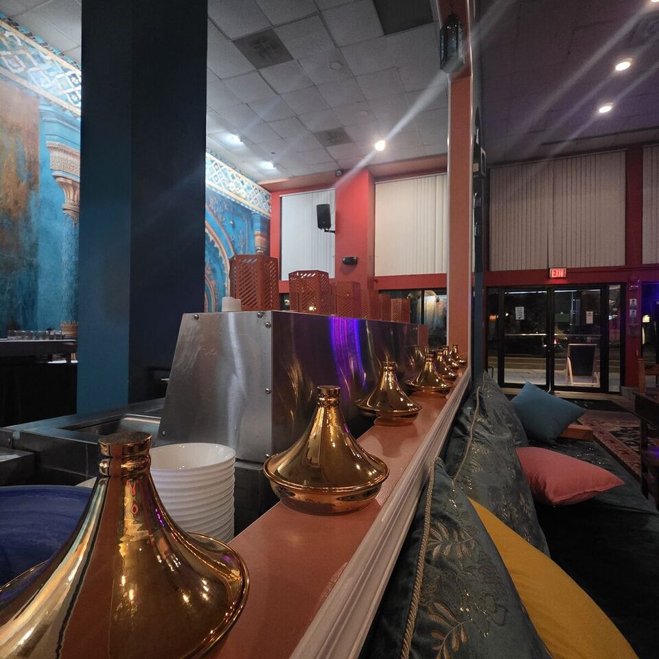 Polished brass tagine lids lined along a banquette with silk cushions