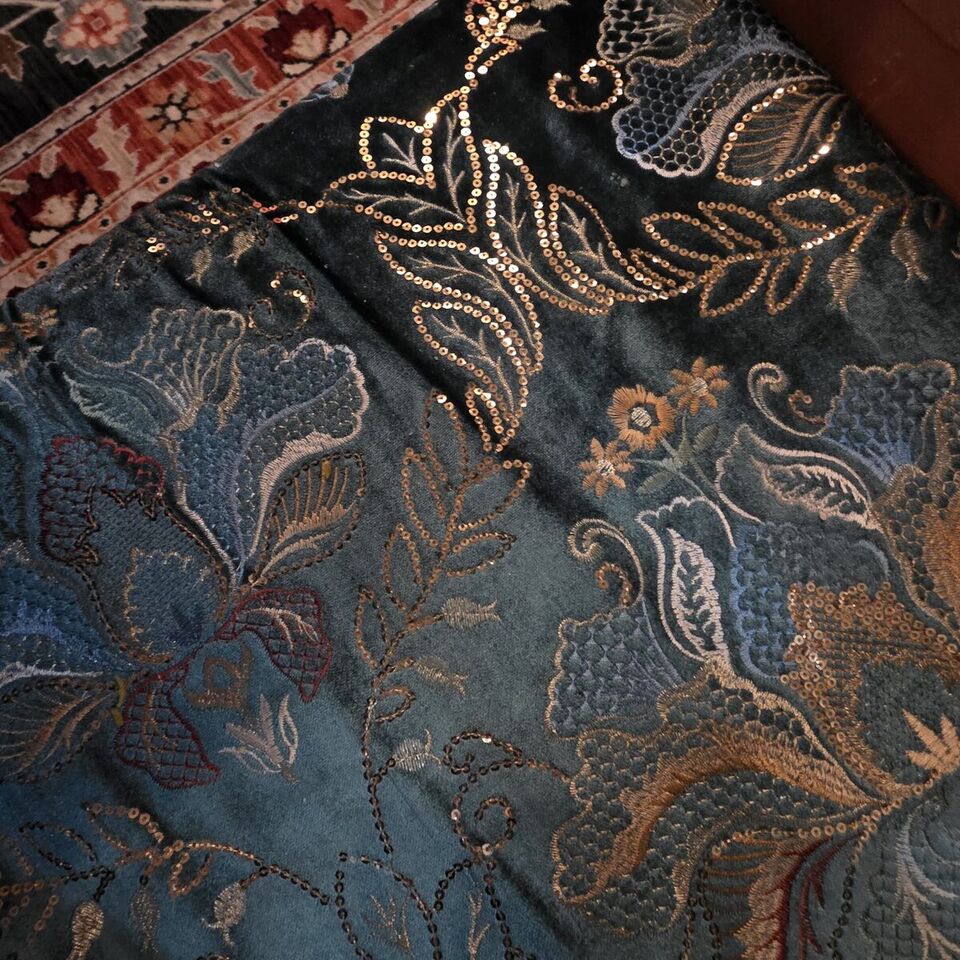 Close-up of teal velvet upholstery with gold sequined floral embroidery