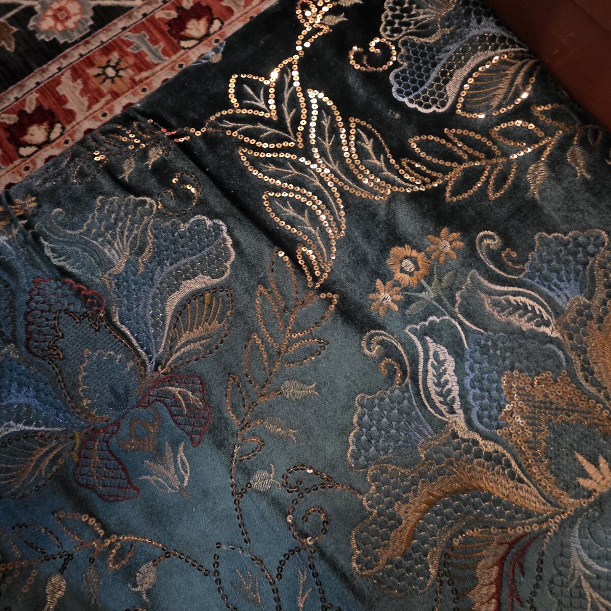 Close-up of teal velvet upholstery with gold sequined floral embroidery